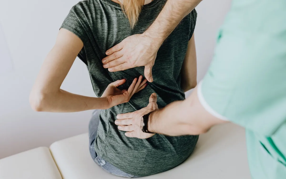 Clinician examining a seated woman’s back