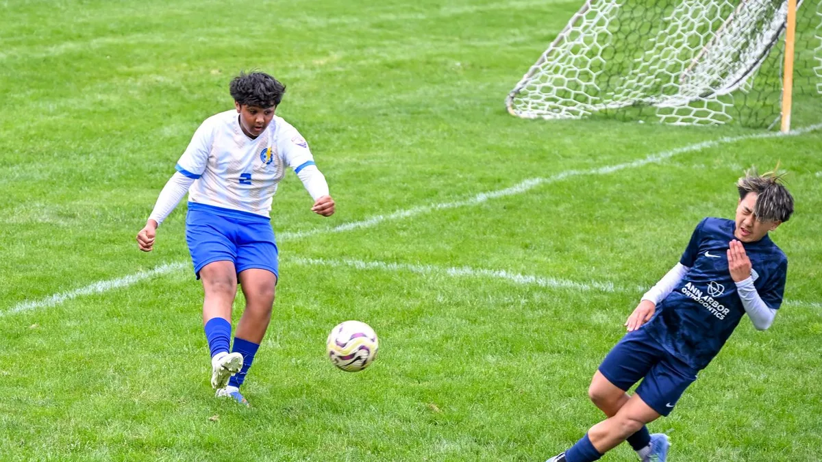 Two young soccer players competing for the ball on a field.