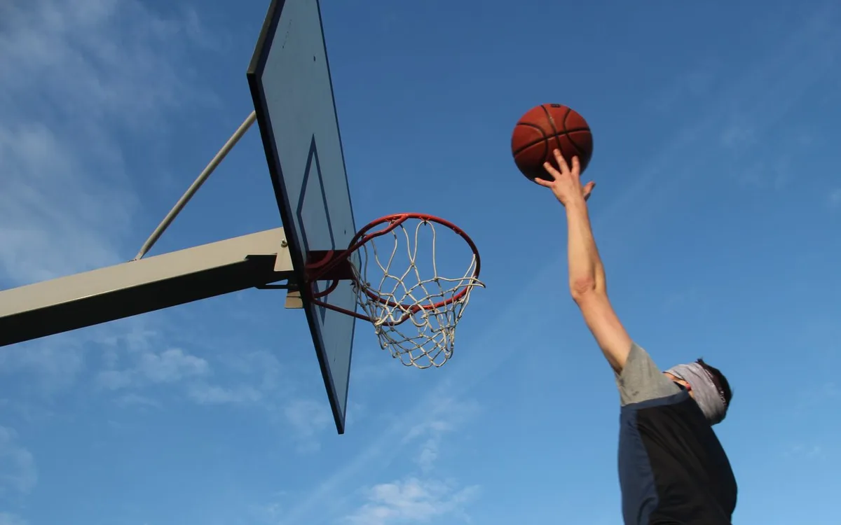 Basketball player jumping toward an outdoor hoop