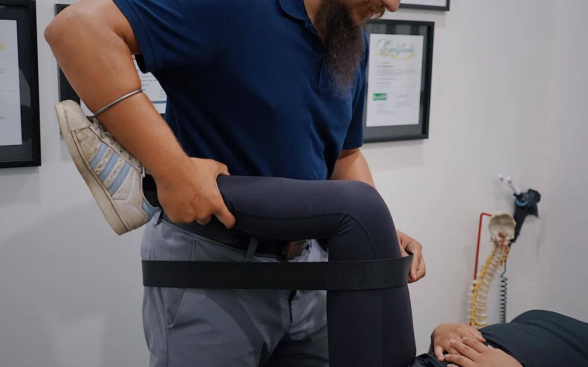 A physiotherapist supports a woman’s bent leg during rehabilitation.