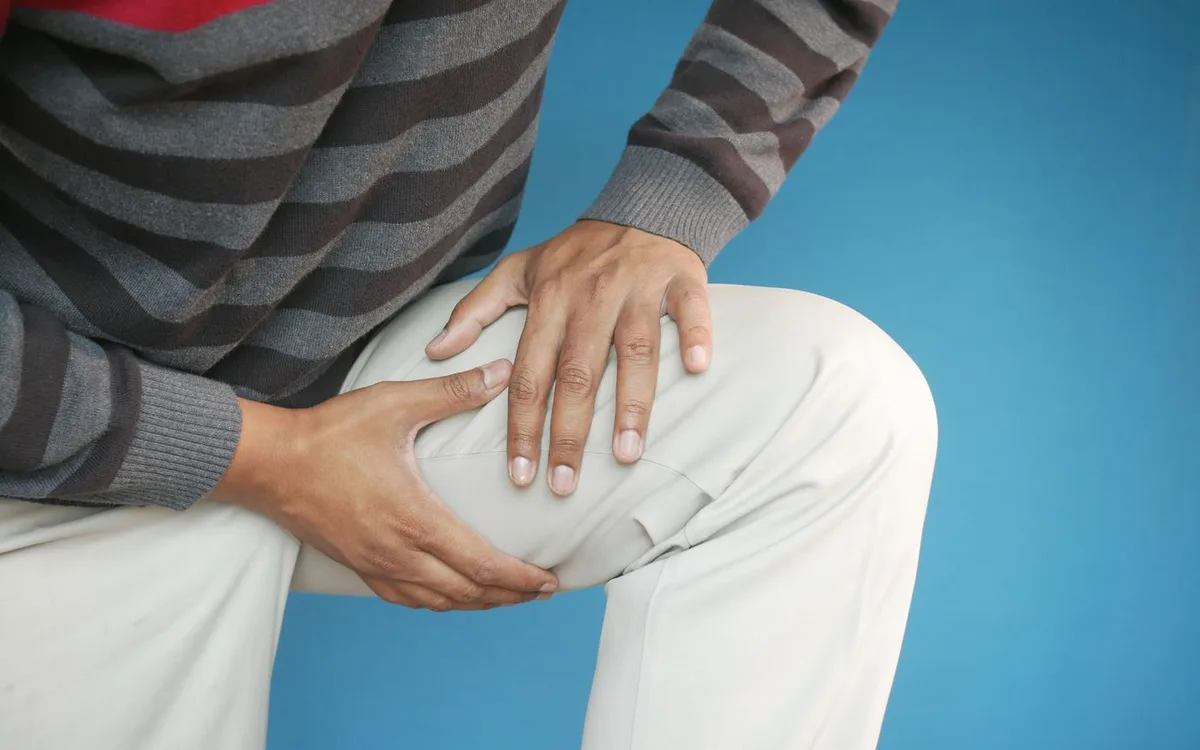 Close-up of hands resting on a bent knee