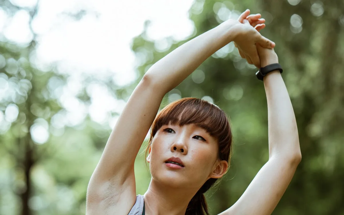 Woman stretching her arms in a green park