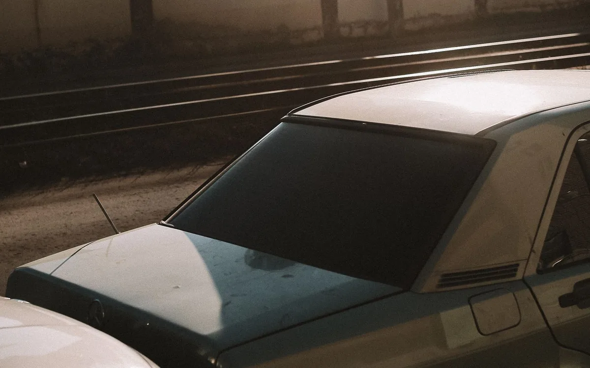 A damaged car photographed beside another vehicle on a road.